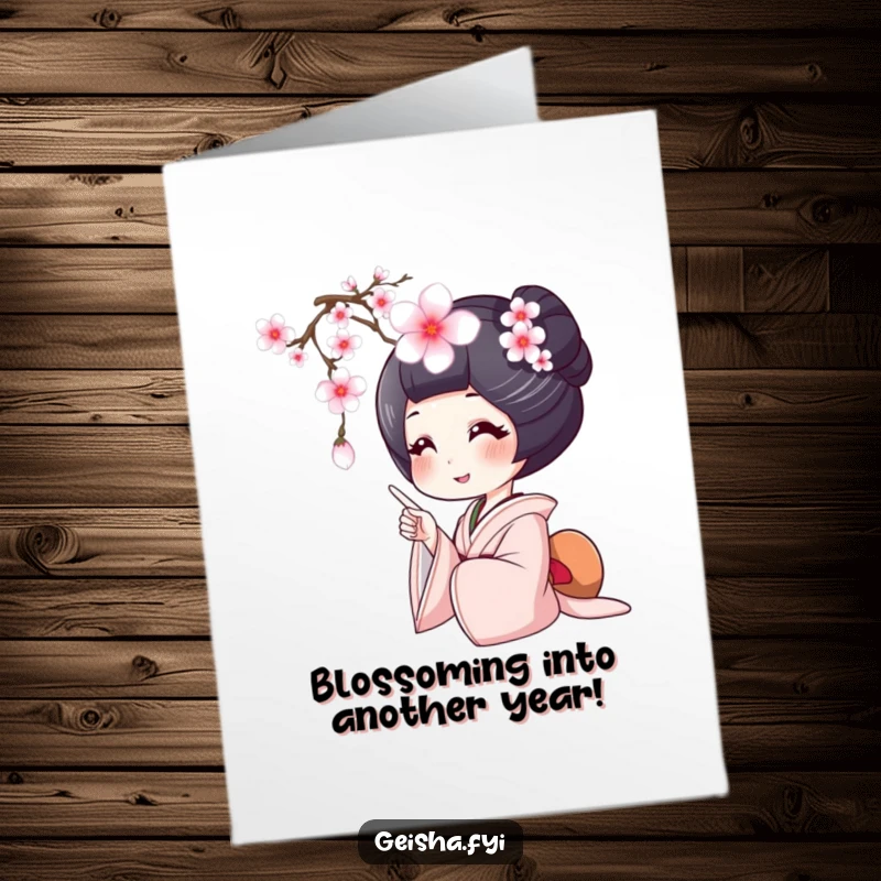 Free printable happy birthday card with a geisha smiling wide, pointing at a delicate falling cherry blossom, celebrating beauty.